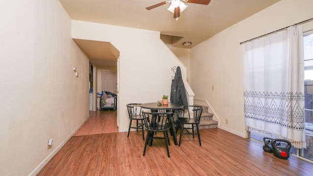 dining space with a ceiling fan, stairway, baseboards, and wood finished floors