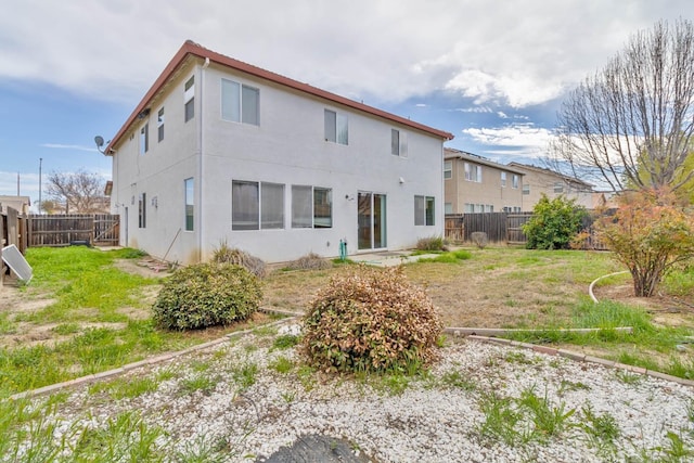 back of property featuring a fenced backyard, a lawn, and stucco siding