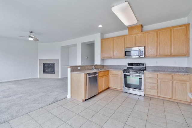 kitchen featuring light carpet, stainless steel appliances, light countertops, and open floor plan