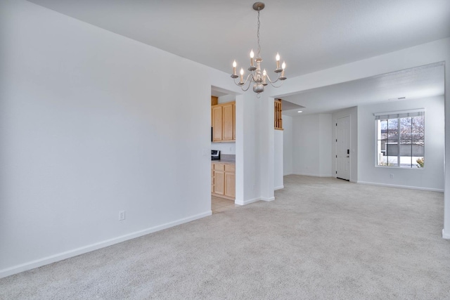 unfurnished living room featuring baseboards, a chandelier, and light colored carpet