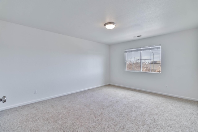 spare room featuring carpet floors, visible vents, and baseboards