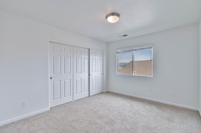 unfurnished bedroom featuring a closet, baseboards, visible vents, and carpet flooring