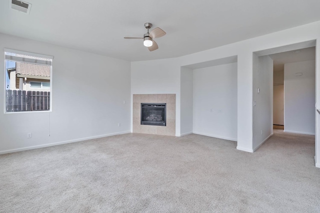 unfurnished living room with a fireplace, light colored carpet, visible vents, a ceiling fan, and baseboards