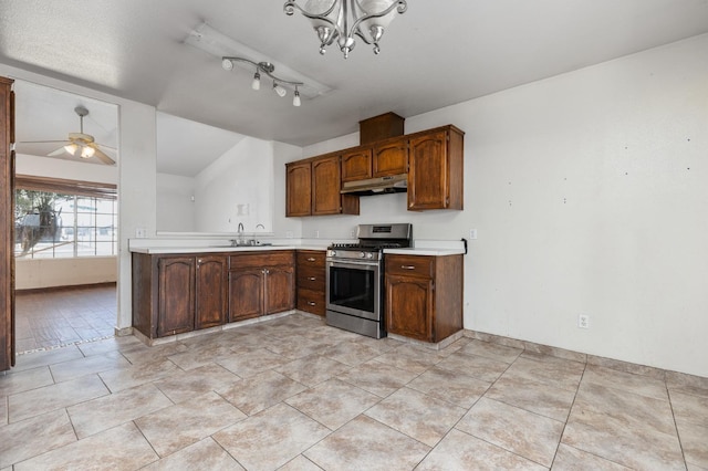 kitchen featuring vaulted ceiling, light countertops, under cabinet range hood, pendant lighting, and gas stove