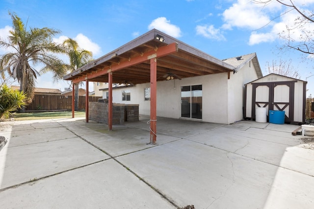 rear view of property with an outbuilding, a storage unit, a patio area, and a ceiling fan