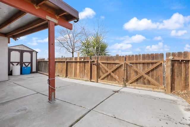 view of patio featuring an outbuilding, a gate, fence, and a storage unit