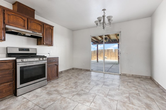 kitchen featuring decorative light fixtures, light countertops, gas stove, a chandelier, and under cabinet range hood