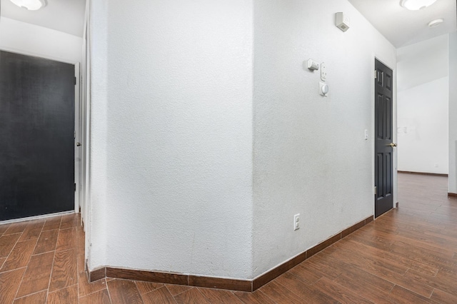 corridor with dark wood-style floors and baseboards