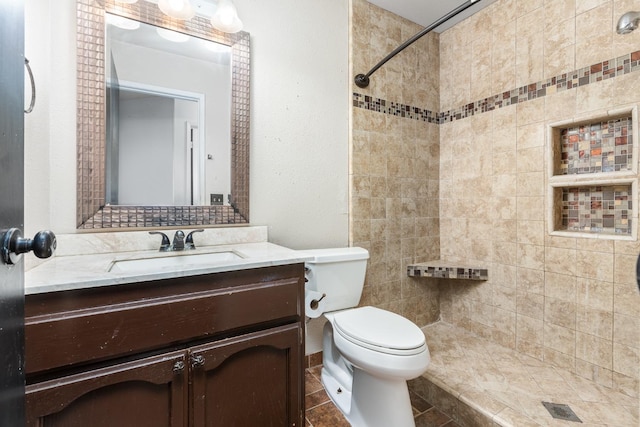 full bath featuring toilet, tiled shower, and vanity