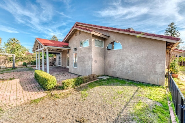 back of house featuring a patio, a lawn, fence, and stucco siding