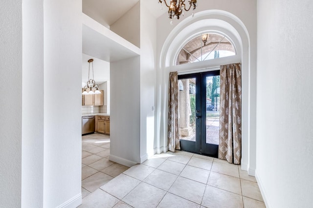 foyer with light tile patterned floors, baseboards, a high ceiling, french doors, and a notable chandelier