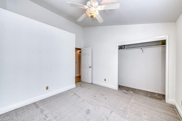 unfurnished bedroom featuring lofted ceiling, a closet, light colored carpet, ceiling fan, and baseboards