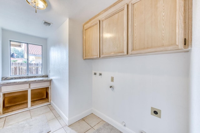 clothes washing area with light tile patterned floors, hookup for an electric dryer, hookup for a gas dryer, baseboards, and cabinet space