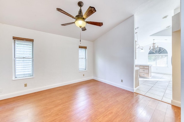 unfurnished room featuring lofted ceiling, light wood finished floors, ceiling fan, and baseboards