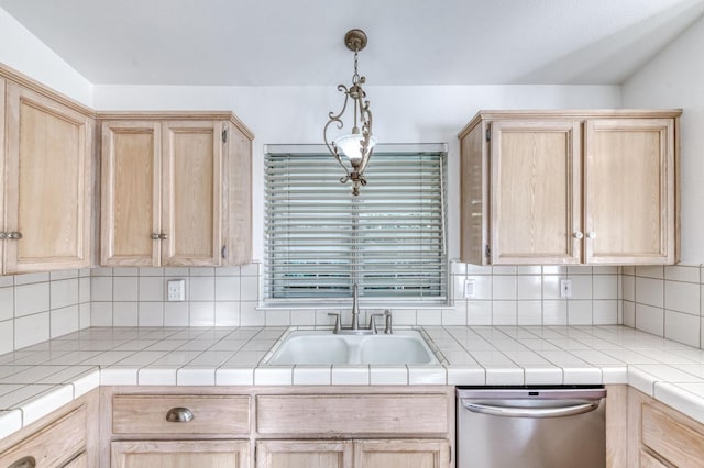 kitchen featuring tile countertops, hanging light fixtures, light brown cabinetry, stainless steel dishwasher, and a sink