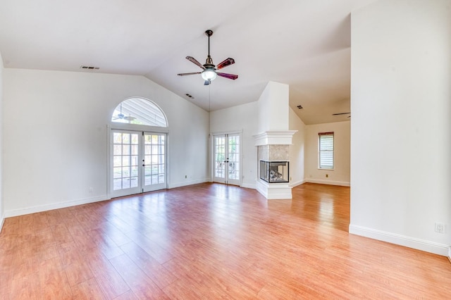 unfurnished living room with light wood-type flooring, visible vents, a multi sided fireplace, and french doors