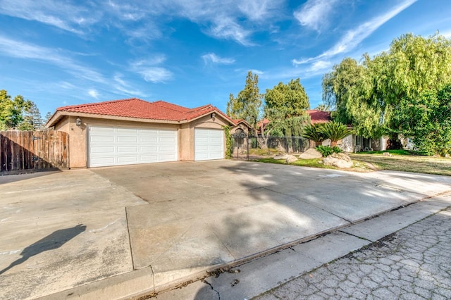 view of front of house featuring a tiled roof, an attached garage, fence, and stucco siding