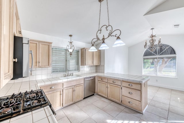 kitchen featuring a peninsula, tile counters, stainless steel appliances, and a sink