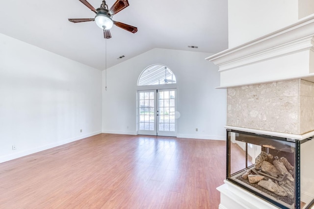 unfurnished living room featuring a ceiling fan, visible vents, wood finished floors, and a glass covered fireplace