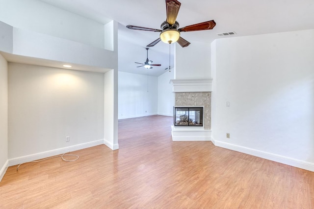 unfurnished living room featuring light wood-type flooring, baseboards, visible vents, and a multi sided fireplace