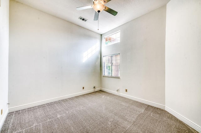 carpeted spare room featuring visible vents, ceiling fan, and baseboards