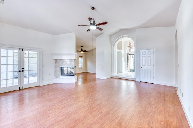 unfurnished living room with light wood-type flooring, plenty of natural light, a fireplace, and arched walkways