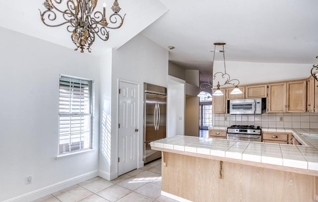 kitchen featuring a peninsula, light brown cabinets, appliances with stainless steel finishes, and tile counters