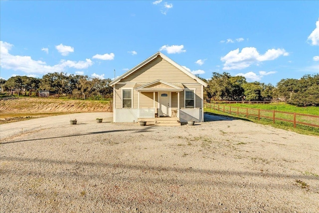 view of front facade featuring a rural view and fence