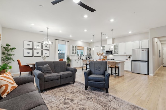 570 Laurel Crest Ave, Madera, CA 93636 - living room featuring a ceiling fan, recessed lighting, light wood-style floors, baseboards, and a chandelier