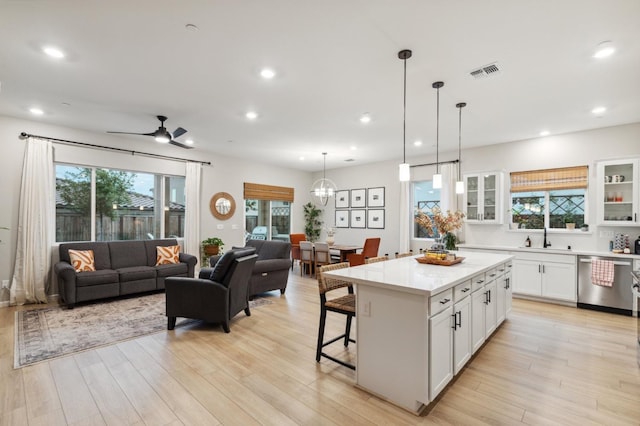 570 Laurel Crest Ave, Madera, CA 93636 - kitchen with stainless steel dishwasher, open floor plan, light countertops, white cabinetry, and a kitchen bar