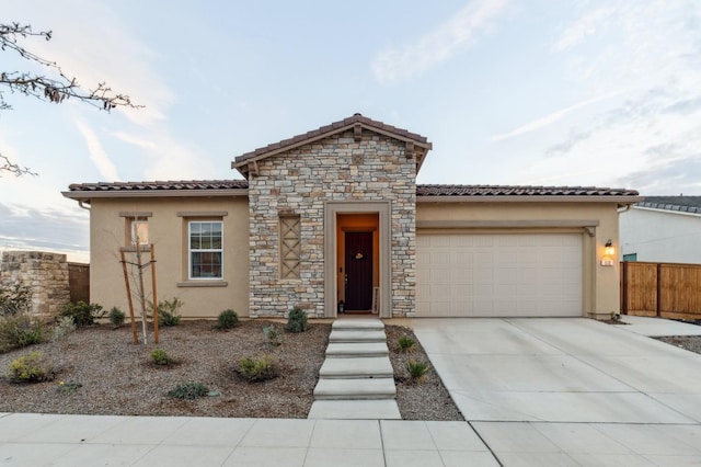 mediterranean / spanish home with concrete driveway, a tiled roof, an attached garage, and stucco siding