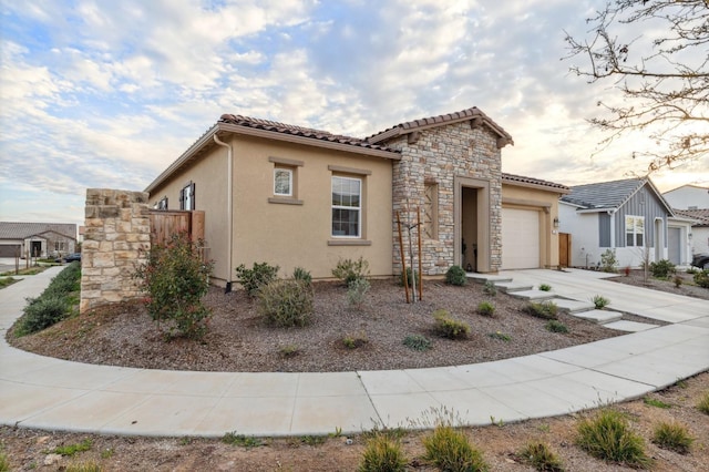 mediterranean / spanish-style home with driveway, a garage, stone siding, a tiled roof, and stucco siding