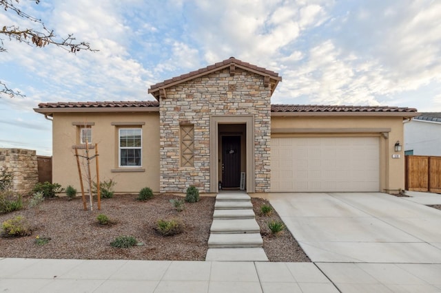 mediterranean / spanish house with a garage, concrete driveway, a tile roof, and stucco siding