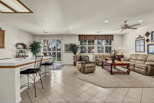 living area featuring light tile patterned floors, plenty of natural light, ceiling fan, and a textured ceiling