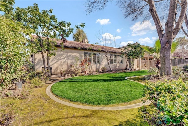 rear view of property featuring a yard, a chimney, fence, and stucco siding