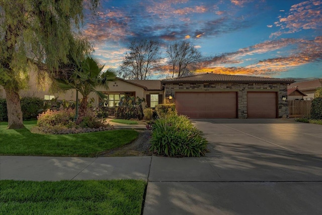 view of front of property with stone siding, driveway, an attached garage, and stucco siding