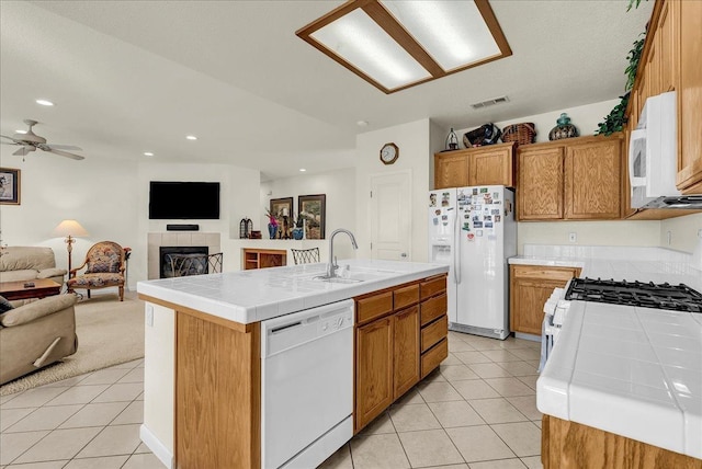 kitchen with tile counters, white appliances, visible vents, and a sink