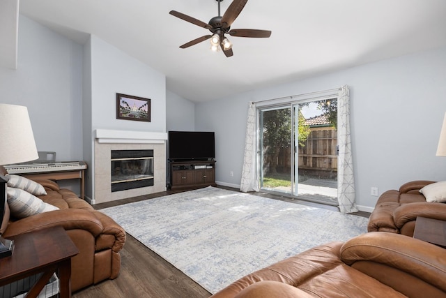 living area featuring a tiled fireplace, baseboards, lofted ceiling, and wood finished floors