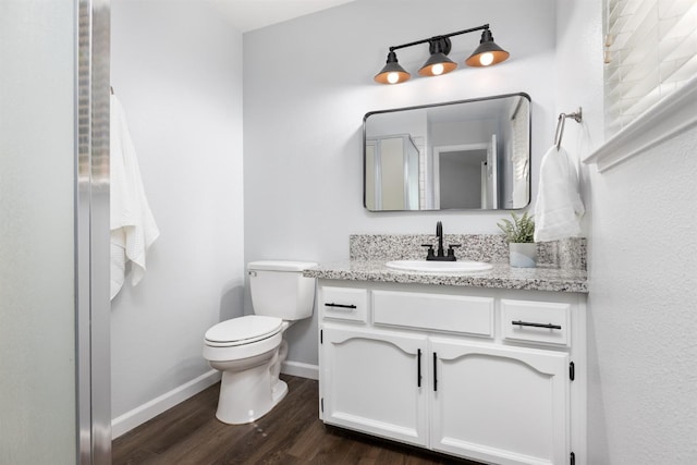 bathroom with baseboards, toilet, wood finished floors, and vanity