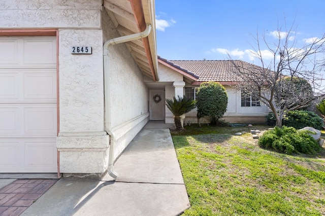 property entrance with a garage, a tile roof, and stucco siding