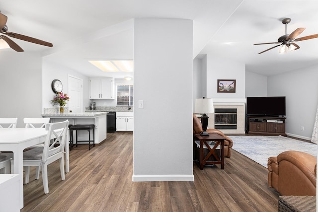 living room with ceiling fan, dark wood-style flooring, and a tiled fireplace