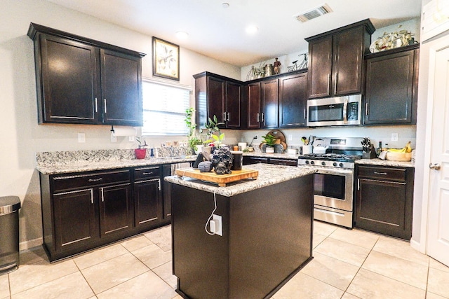 kitchen featuring light tile patterned floors, stainless steel appliances, a kitchen island, visible vents, and light stone countertops