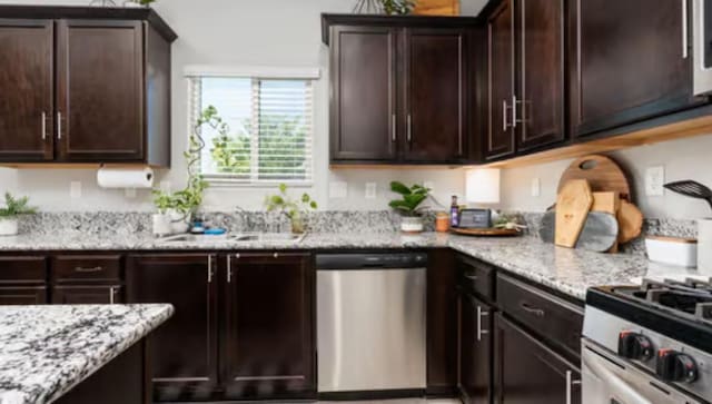 kitchen with a sink, dark brown cabinetry, appliances with stainless steel finishes, and light stone counters