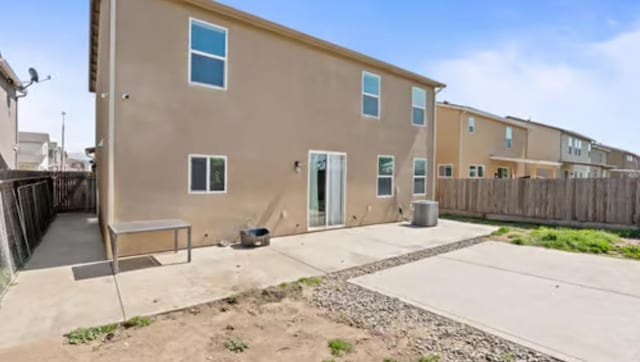 rear view of property featuring a fenced backyard, stucco siding, and a patio