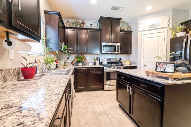 kitchen featuring light tile patterned floors, visible vents, appliances with stainless steel finishes, a sink, and dark brown cabinetry