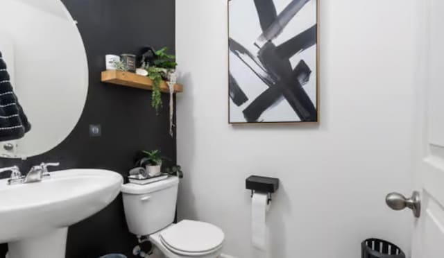 half bath featuring toilet and a sink