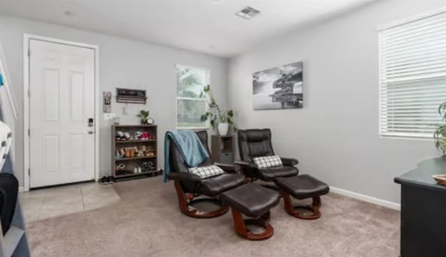 sitting room featuring baseboards, carpet flooring, visible vents, and tile patterned floors
