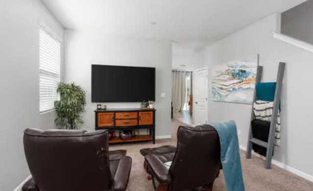 living area featuring light carpet and baseboards