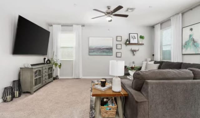 living room with baseboards, visible vents, a ceiling fan, and light carpet