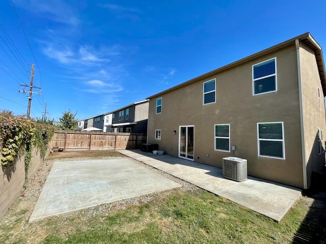 rear view of property with a patio, stucco siding, a fenced backyard, and central AC
